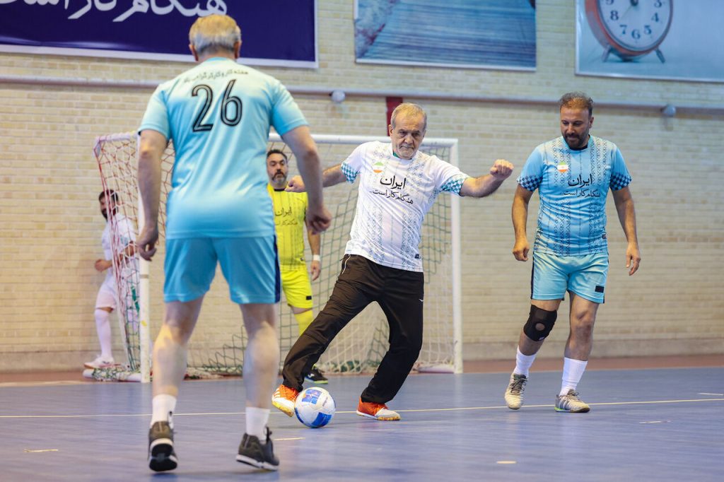 علی پروین و کاظم اولیایی با سرمربیگری حسین شمس کادر فنی تیم پیشکسوتان و علی اکبر سلطانی و چکشیان کادر فنی تیم کارگران را تشکیل می‌دادند. رئیس جمهور در نیمه نخست با پیراهن تیم کارگری و در نیمه دوم در تیم پیشکسوتان به میدان رفت. پیش از بازی دو تیم با حضور دکتر پزشکیان عکس یادگاری گرفتند. در تیم پیشکسوتان فوتبال چهره‌هایی چون محمدرضا حیدریان، مصطفی نظری، محمد انصاری، مجتبی شیری، علی صانعی، حمید درخشان، صادق ورمزیار و محمد طاهری حضور داشتند.